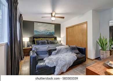 Masculine Bedroom Features Gray Accent Wall And White Ceiling Over Sea Art Over Dark Gray Bed With Black Leather Sofa Placed At Foot Of The Bed. Northwest, USA
