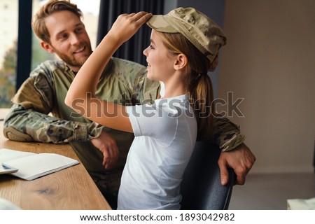 Masculine happy military man making fun with her daughter at home