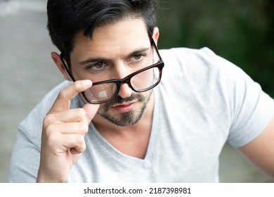 Masculine Man Portrait Looking Over His Glasses Off Camera. Boy Posing With Glasses To See Under The Eyes With An Interested Look And Serene Gesture. Modern Man Looking Over His Glasses