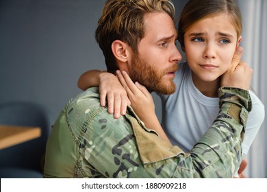 Masculine Military Man Hugging Her Crying Daughter While Kneeling Indoors