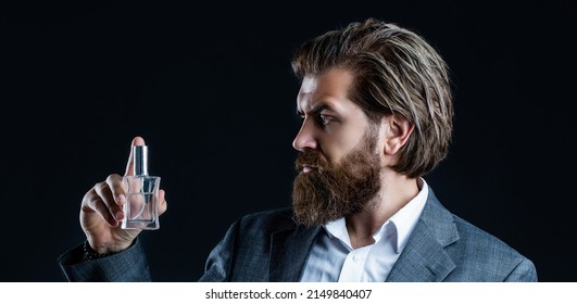 Masculine Perfume, Bearded Man In A Suit. Male Holding Up Bottle Of Perfume. Man Perfume, Fragrance. Perfume Or Cologne Bottle And Perfumery, Cosmetics, Scent Cologne Bottle, Male Holding Cologne.