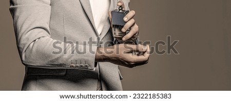 Masculine perfume, bearded man in a suit. Male holding up bottle of perfume. Man perfume, fragrance