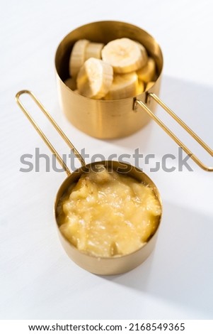 Mashed overripe bananas and sliced riped bananas in metal measuring cups. Foto stock © 