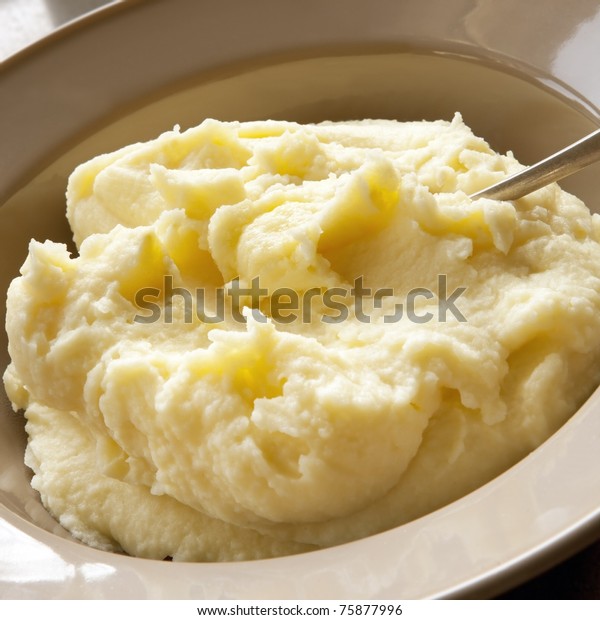 Mashed potato with\
spoon, in serving bowl.