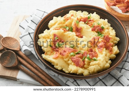 Mashed potatoes. Bacon mashed potatoes with green onion, pepper and cheddar cheese in bowl on old wooden backgrounds. Delicious creamy mashed potatoes. Top view.