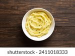 Mashed potatoes, boiled puree in bowl over wooden background with free space. Healthy comfort food. Top view, flat lay