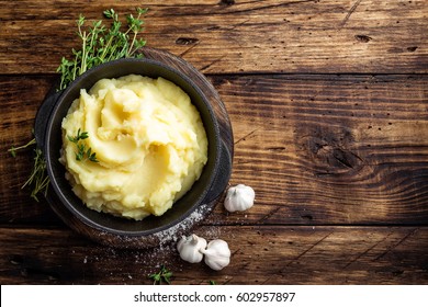 Mashed potatoes, boiled puree in cast iron pot on dark wooden rustic background, top view - Shutterstock ID 602957897