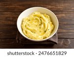 Mashed potatoes, boiled puree in white bowl on wooden background. Healthy comfort food. Close up view