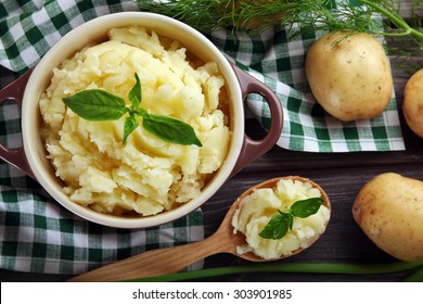 Mashed potatoes in bowl on wooden table with checkered napkin, top view