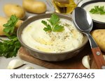 Mashed potatoes in bowls, spoon and ingredients on gray background, close up