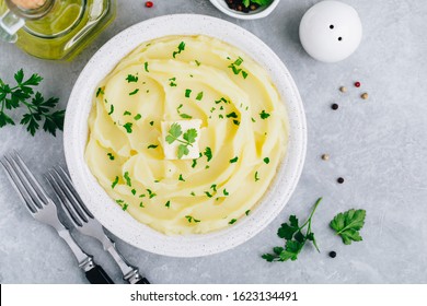 Mashed Potatoes with butter and fresh parsley in a white bowl on gray stone concrete background. Top view, copy space - Shutterstock ID 1623134491