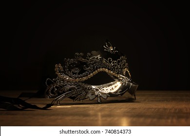 Mask of mystery. A portrait of a venetian mask on a wooden table surrounded by darkness.