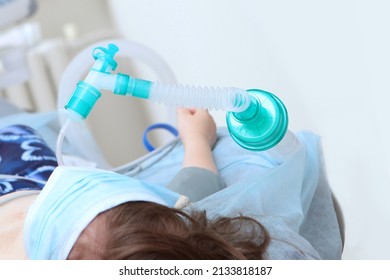 A Mask With Oxygen On The Child's Face. The Child Is Under Anesthesia. Surgery Under General Anesthesia. Saving A Child's Life. The Child Is Out Of Focus.