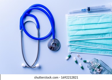 Mask With Pills, Stethoscope, Syringe Medical Supply Objects Isolated On Blue Background, Top View, Flat Lay, Overhead Shot, Virus Protection Concept.