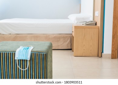 Mask Resting On An Out-of-focus Striped Stool In A Hotel Room In Mallorca, Background In Focus. New Habits In Responsible Tourism