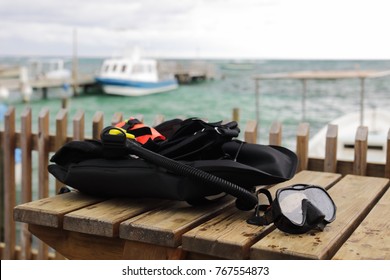  Mask And Scuba Diving Equipment On Wood Table In Caribbean Sea Wit Boat At Background 