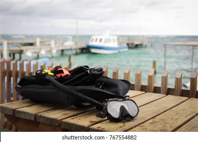  Mask And Scuba Diving Equipment On Wood Table In Caribbean Sea Wit Boat At Background 