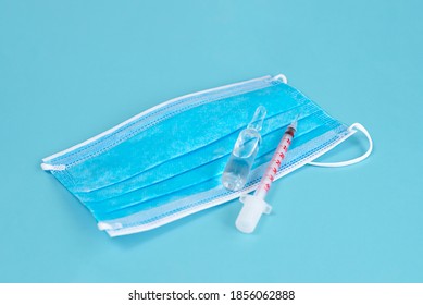 Mask With Syringe Medical Supply Objects Isolated On Blue Background, Top View, Flat Lay, Overhead Shot, Virus Protection Concept. Coronavirus COVID-19 Vaccine