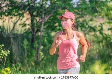 Mask Wearing COVID-19 Outdoor Run Exercise. Asian Woman Running Outside With Face Covering While Exercising Jogging On Run Sport Workout In Summer Park Nature. Pink Mask, Cap, Tank Top.