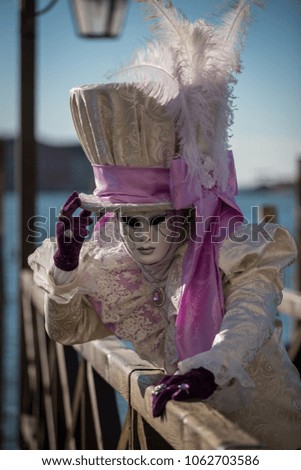 Mask with white hat in Venice carnival near Piazza San Marco by the edge of lagoon