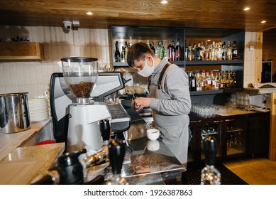 A Masked Barista Prepares Delicious Coffee At The Bar In A Cafe. The Work Of Restaurants And Cafes During The Pandemic.