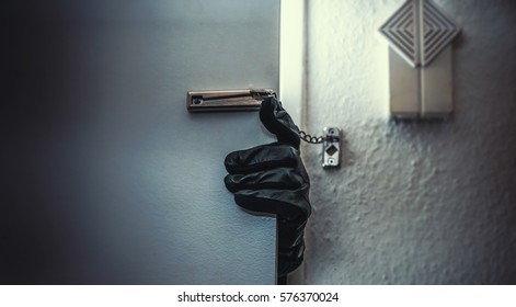 masked burglar with crowbar breaking and entering into a victim's home  - Shutterstock ID 576370024