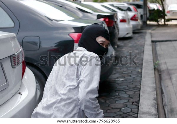 Masked burglar
wearing a balaclava ready to burglary against car background.
Insurance crime concept.
