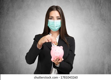 Masked Businesswoman Putting Money In A Piggy Bank, Coronavirus Savings And Investments Concept