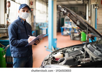 Masked Car Mechanic Repairing A Car, Covid Coronavirus Work Concept