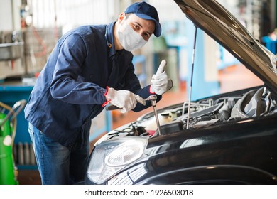 Masked Car Mechanic Repairing A Car, Covid Coronavirus Work Concept