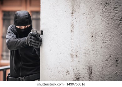 Masked Criminal, A Fugitive, Aiming With A Gun, Hiding Behind A Wall