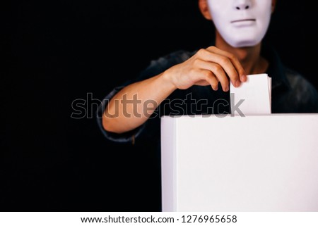 Masked criminal holding ballot paper casting fake vote at a polling station for election vote in black background