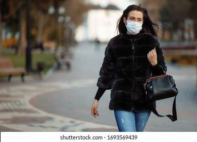 A masked girl is walking along the street. Coronavirus infection (COVID-19) - Powered by Shutterstock