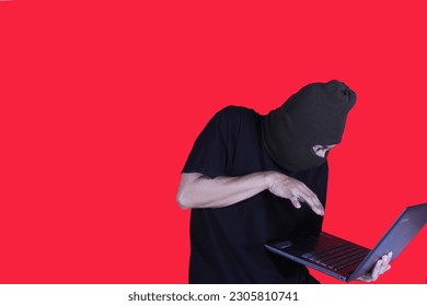 Masked Hacker is Using Computer for Organizing Massive Data Breach Attack on Corporate Servers. They're in Underground Secret Location Surrounded by Displays and Cables.