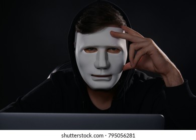 Masked man hacking server in dark room - Shutterstock ID 795056281