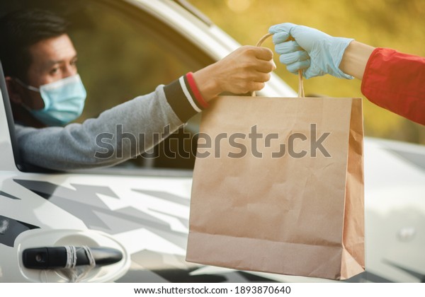 Masked man, restaurant\
customer, in car to pick up food on Christmas Day Online food\
delivery concept