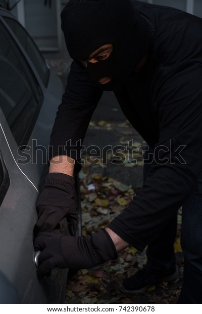 Masked man stealing a\
car