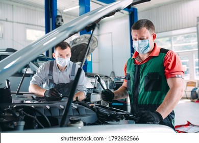 A masked mechanic checks the car at the service station