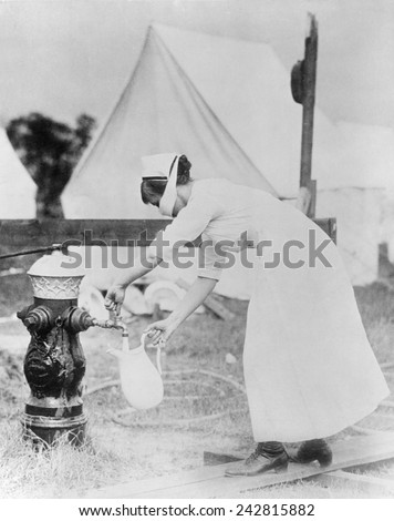 Masked nurse pumping water at a field hospital during the 1918 Spanish flu pandemic. Photographed in United States, September 1918.