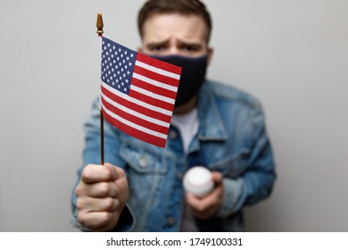 masked protesting young man holding an american flag. riots in america.