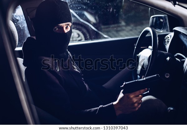 Masked terrorist with\
pistol gun in car