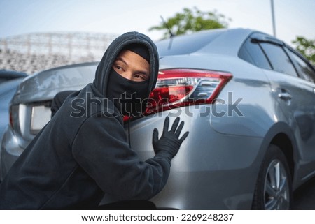 Masked thief in action before burglary. Car thief criminal concept.