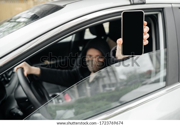 masked woman, a car driver, shows a smartphone\
screen with a digital pass to travel through the city. The concept\
of coronovirus epidemic and\
pandemic.