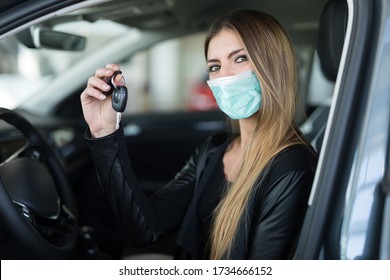 Masked Woman Showing The Key Of Her New Car In A Car Dealer Saloon During Coronavirus Pandemic