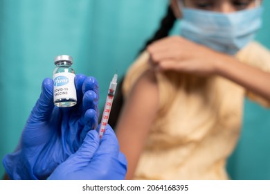 Maski, India - October 26, 2021 : Selective Focus On Vaccine Bottle - Kid With Medical Face Mask Getting Vaccinated Pfizer's Covid-19 Or Coronavirus Children Vaccine At Hospital