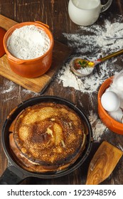 Maslenitsa, Pancake Day. A Stack Of Pancakes On A Pan, Vintage Kitchen Utensils And Baking Ingredients On A Dark Wooden Table