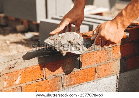 Mason applying mortar to bricks during construction at building site