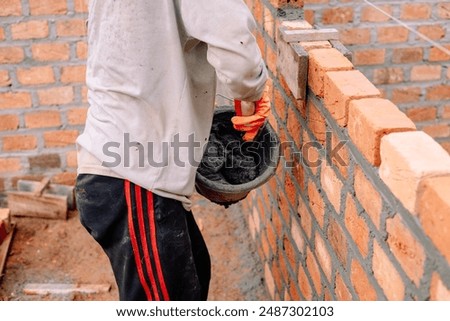 mason bricklayer installing brick blocks to build a wall at a construction site, bricklayer worker installing concrete blocks to build a wall at a construction site
