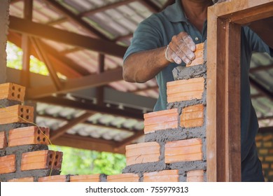 A mason builds brick wall in the house
