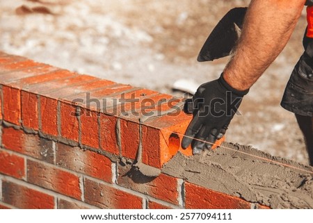 Mason carefully stacking bricks with mortar to build a sturdy wall at a construction site